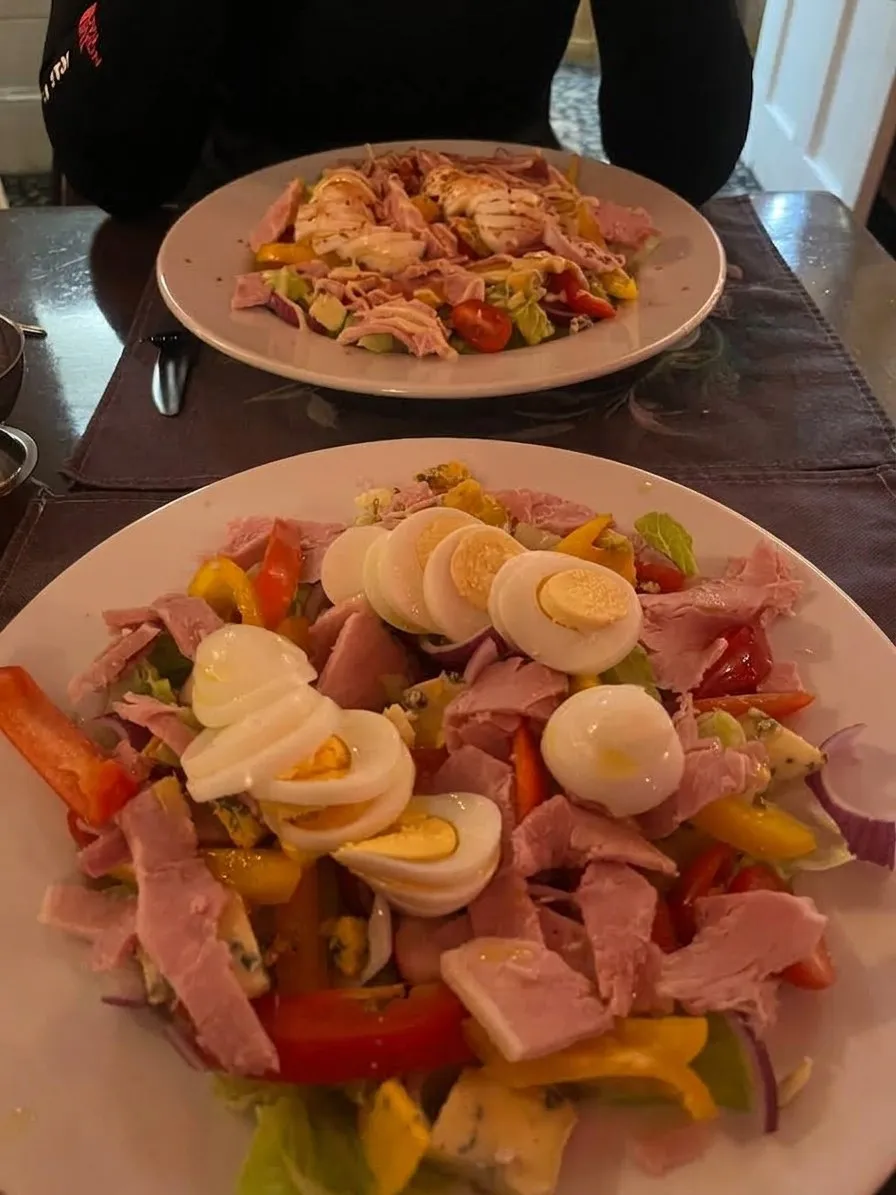 A large salad with ham, boiled eggs and peppers